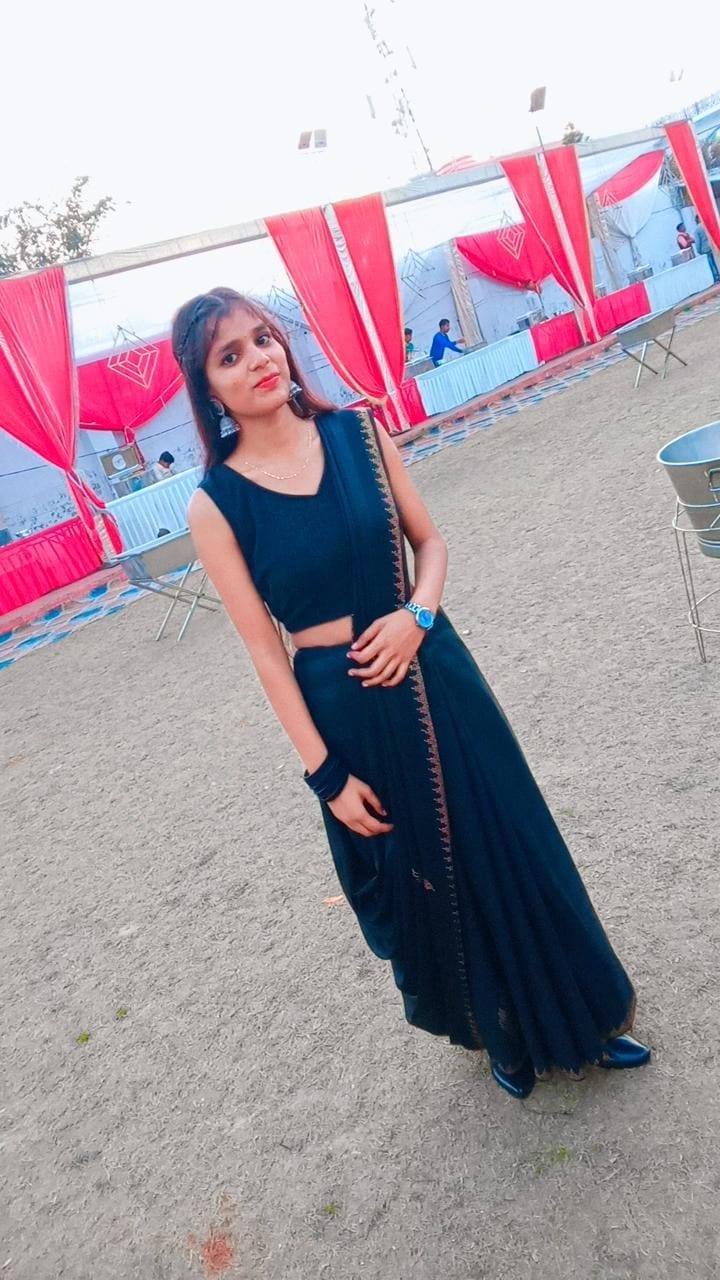 Saumya in a black saree at an outdoor celebration with red-and-white décor
